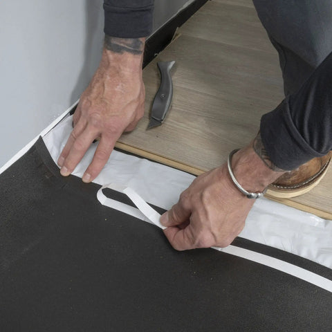 Hands installing Straight Shooter Floor Underlayment For Laminate And Engineered Wood, 600 Square Foot Roll in a room.