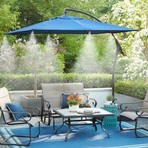 Outdoor patio with blue umbrella and misting system 26 foot kit with brass nozzles and three quarter inch brass adapter cooling area