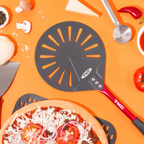 TKC 9-inch perforated pizza peel with red handle; aluminum turning spatula, top-down view