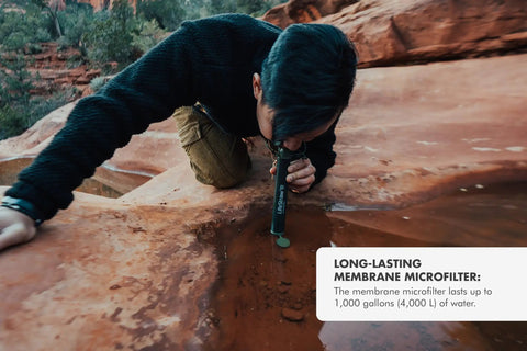 Individual using Personal Water Purifier For Hiking Camping Travel And Emergency Prep Delivers Safe Drinking Water By Filtering Out Bacteria Parasites And Microplastics So You Can Stay Ready For Any Backcountry Adventure to drink from rock pool.