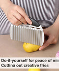 Large stainless steel crinkle cutter with black handle slicing a potato