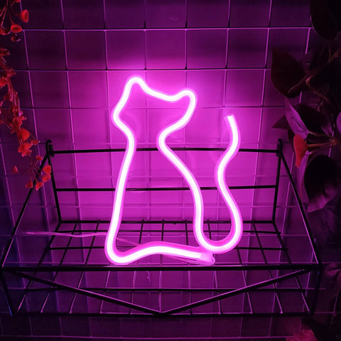 Pink Cat Neon Sign LED Light Powered By USB Or Three AA Batteries for desk table decor in pink glow on tiled wall.