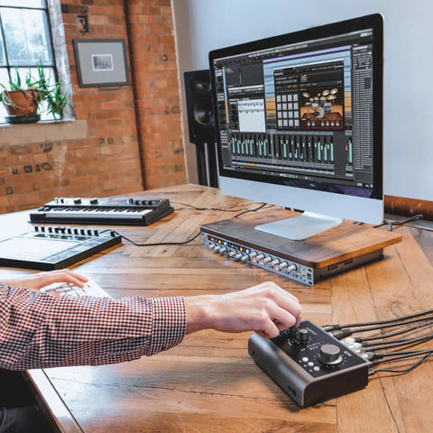 Person using iD14 MKII USB-C Audio Interface with computer in modern studio, showcasing dual headphone outputs and monitor mix.