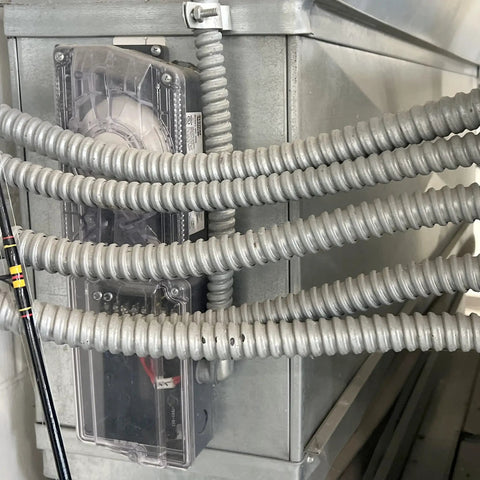 1 Inch By 25 Foot Galvanized Steel Flexible Conduit For Electrical Wiring, Smooth Interior For Easy Wire Pull, installed on a panel.