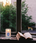 Electric Yahrzeit Candle LED Votive Flameless Memorial Light Battery Operated in a window with an open book nearby.