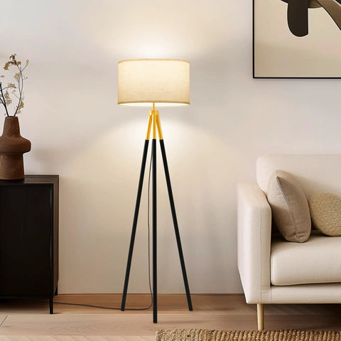 Levi LED Floor Lamp with tall black and gold tripod next to sofa, ideal for living room modern decor, standing lamp for office.