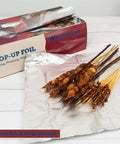 Heavy Duty Aluminum Foil Sheets 500 Pop Up Interfolded 12 By 12 Inch Sheets displayed with grilled skewers