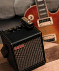Wireless Guitar System With Rock-Solid 2.4G Transmission, 24-Bit/48kHz Audio beside guitar and amplifier on wooden table.