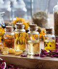 Glass bottles filled with essential oils, cork stoppers, surrounded by dried herbs and flowers, on a wooden table.