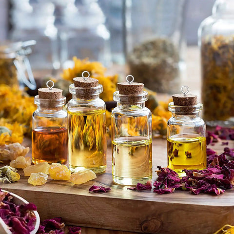 Glass bottles filled with essential oils, cork stoppers, surrounded by dried herbs and flowers, on a wooden table.