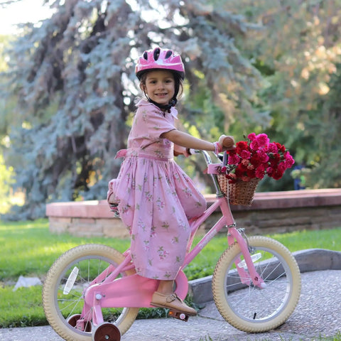 Girl riding 14 Inch Pink Princess Kids Bike for Girls Aged 3 To 5 with Training Wheels, basket, and durable steel frame.