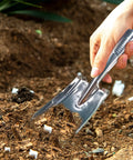 Hand using stainless steel garden trowel for transplanting in soil, part of the Stainless Steel Garden Shovel And Trowel Hand Tools Set For Transplanting Weeding Moving And Smoothing Digging And Planting Durable Ergonomic Do It All Three Pack For Small Gardens.