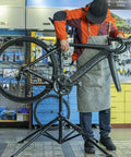 Heavy Duty Bike Repair Stand for Easy Home Maintenance with tool tray, holding a road bike in a workshop environment.