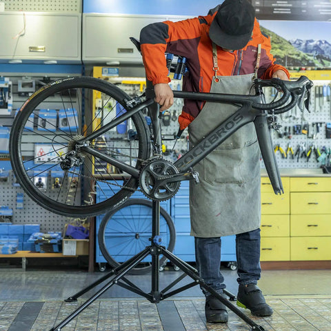 Heavy Duty Bike Repair Stand for Easy Home Maintenance with tool tray, holding a road bike in a workshop environment.