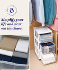 Three Tier Rolling Storage Cart With Removable Wheels In White Frame, Clear Bin Drawers, shown in a closet with folded clothes.