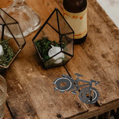 Compact Bicycle Shaped Multitool Keychain Made From Durable Stainless Steel For On The Go Bike Repairs on wooden surface