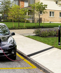 Heavy Duty PVC Floor Cord Cover For Wires And Cables black ramp in use over sidewalk, preventing trip hazards, for home or office safety.