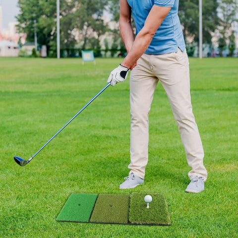 Man practicing with 3-In-1 Golf Practice Mat With Realistic Turf Surfaces For Hitting Swing And Putting Training Indoor Outdoor Practice Aid Wind Shear Upgrade Includes 35mm Rough Turf 16mm Green Turf And 10mm Fairway Turf on grass