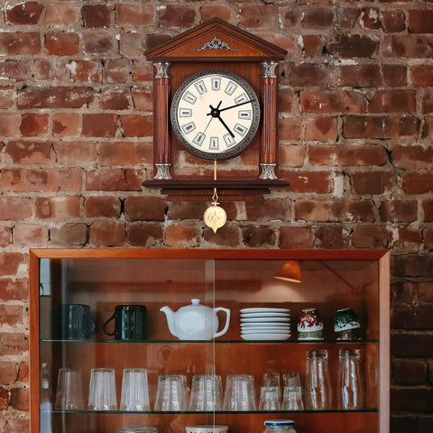 Wooden wall clock with golden pendulum, Metal Clock Pendulum Replacement Part 8.27 By 2.36 Inch visible against brick wall