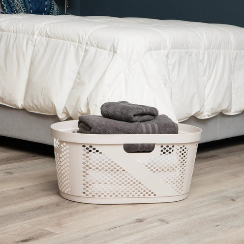40 Liter Laundry Basket With Lightweight Plastic Build Ivory Wicker-Look Hamper beside a bed in a bedroom.