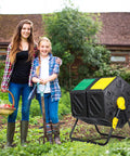 37 Gallon Dual Chamber Tumbling Composter With Two Sliding Doors in a garden setting next to smiling gardeners