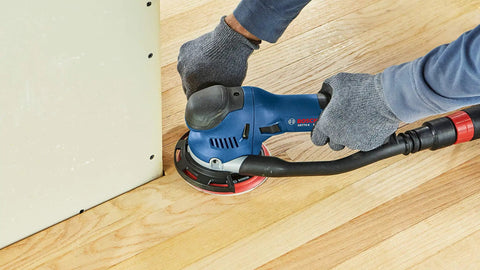 Person using six inch hard hook and loop sanding pad with multi hole dust extraction, fiberglass reinforced backing plate.