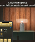 White Smart Light Starter Kit With Bridge And Two 75W A19 E26 LED Soft White Bulbs shown in lamp with app control on phone screen