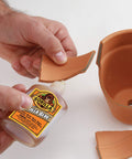 Hands using Heavy Duty Waterproof Polyurethane Glue For Wood, Metal, Stone, Ceramic, Glass, And Concrete, 2 Ounce Brown Bottle on pottery