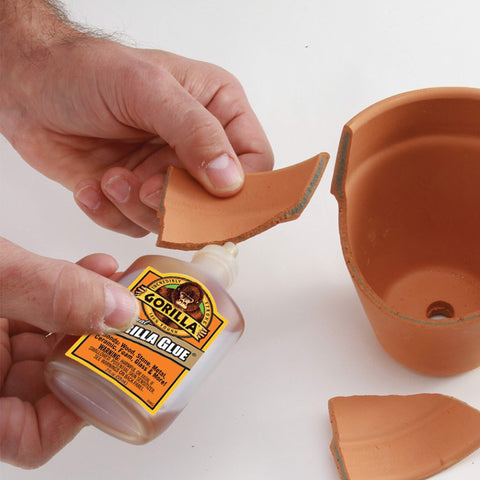 Hands using Heavy Duty Waterproof Polyurethane Glue For Wood, Metal, Stone, Ceramic, Glass, And Concrete, 2 Ounce Brown Bottle on pottery