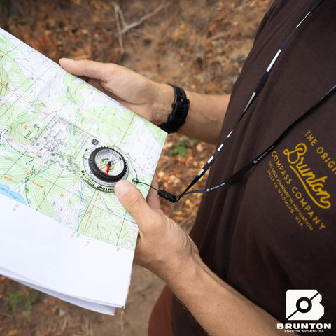 Person holding map with TruArc10 Baseplate Compass For Weekend Camping With Reversible Slide Scale And Magnified Readout