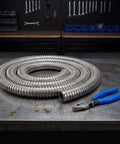 Built Tough Stainless Steel Flexible Wire Conduit For Electrical Cable Routing And High Temperature Rugged Metal Tubing With Wear Resistant Silver Finish Job Site Ready Pro Grade Cable Runner coiled beside pliers on metal workbench.