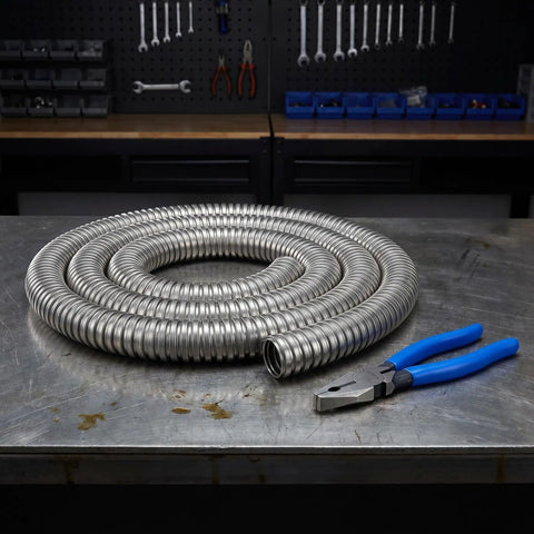 Built Tough Stainless Steel Flexible Wire Conduit For Electrical Cable Routing And High Temperature Rugged Metal Tubing With Wear Resistant Silver Finish Job Site Ready Pro Grade Cable Runner coiled beside pliers on metal workbench.