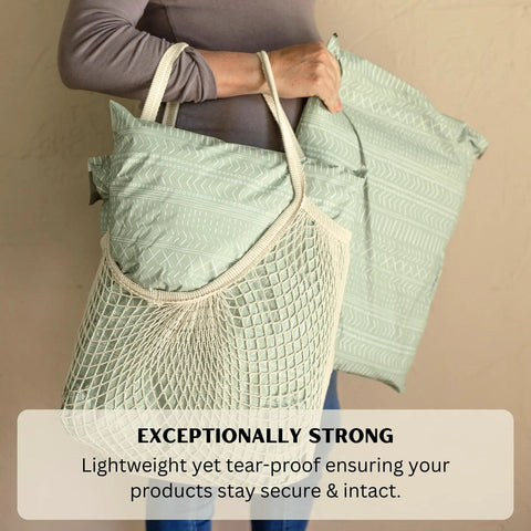 Person holding 14x19 Sage Green Boho mailers in net bag showcasing Extra Large 14x19 Inch Poly Mailers Pack Of 50 Self Sealing Waterproof And Tear Proof Envelopes For Clothing Shipping With Sage Green Boho Design Great For Small Biz Packaging And Durable Protective Mailers