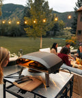 Koda 16 Inch Propane Gas Pizza Oven With 28 MBAR Regulator And Hose Outdoor Portable Oven beside a group on a patio