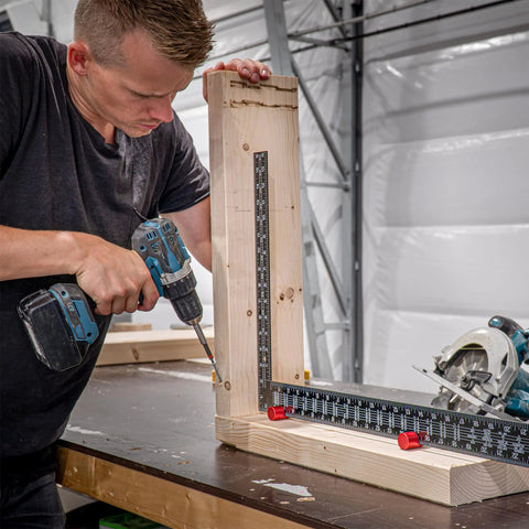 Man using stair gauges for framing square with non slip grip on wooden board in workshop, heavy duty framing jig for speed squares.