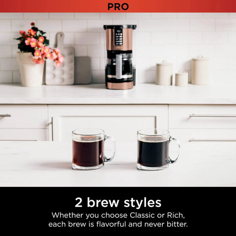 Programmable XL 14 Cup Barista Grade Coffee Maker Pro With Permanent Filter Classic Or Rich Brew Delay Brew Freshness Timer Keep Warm Dishwasher Safe Copper Finish on kitchen counter with two cups of brewed coffee