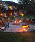Night view of patio with chairs around a fire pit, lit by Three LED Landscape Lights With Bracket In Textured Architectural Bronze Finish 4 Pack.