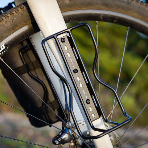 Outpost Cargo Water Bottle Cage With Triple Mount Holes And Straps on bike frame securing gear for easy carry and rugged day ride confidence