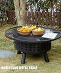 36 Inch Outdoor Fire Pit With Grill And Lid Wood Burning Fire Pit Table 3 In 1 Metal Fire Pit in grassy yard with snacks.