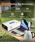 Ready To Rock 5000 Watt Power Inverter Converting 12V DC To 110V AC With Four Household Outlets And Dual USB Ports set up on a table outdoors.