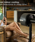 FlexBreeze Pro Mist Fan Indoor Outdoor Chill Machine in charcoal grey beside relaxed woman in living room
