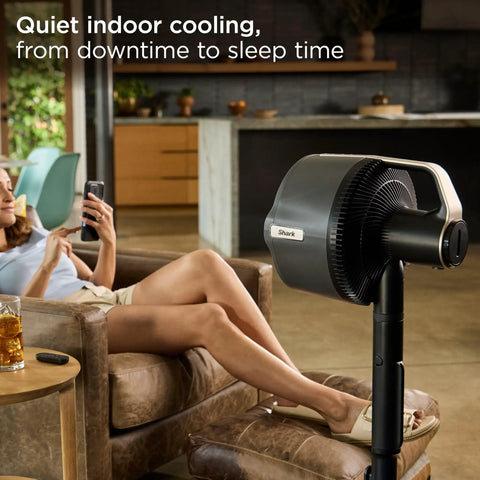 FlexBreeze Pro Mist Fan Indoor Outdoor Chill Machine in charcoal grey beside relaxed woman in living room