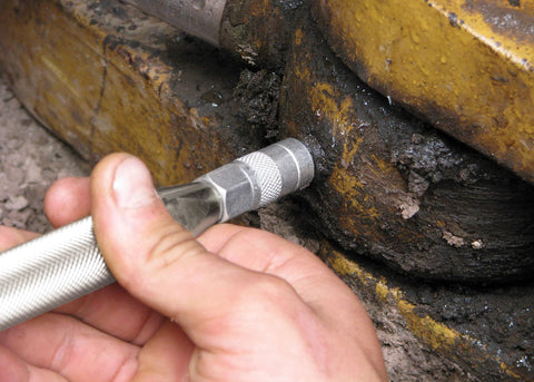 Grease Joint Rejuvenator tool with knurled silver handle being inserted into a rusty joint.