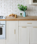 White kitchen with stainless steel oven, wood countertop, and cabinets, featuring matte black pulls for upgraded kitchen cabinetry.