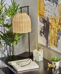 Bahama Table Lamp With Dark Bronze Finish For Warm Coastal Modern Vibes, 24.5in tall, rattan shade, on a desk.