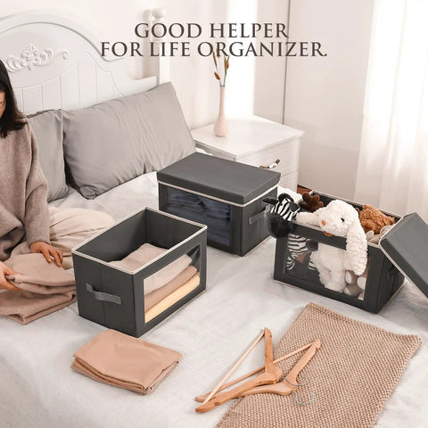 Dark Grey 3 Pack Fabric Storage Bins With Lid And Peek Window Collapsible Closet Organizers Tough Handle Crates on bed with folded clothes and toys.