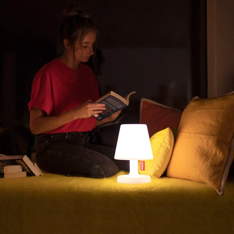 A woman reading by the Tiny Rechargeable LED Lamp 2.0 Go Anywhere Dimmable Table Light For Indoor And Outdoor Use Bright 58 Lumens.