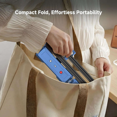 Artilume T1 portable laser engraver, blue body with black rails, being placed into a beige tote bag