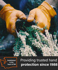 Close-up of a pair of orange nitrile work gloves with raised diamond grip gripping soil and plants