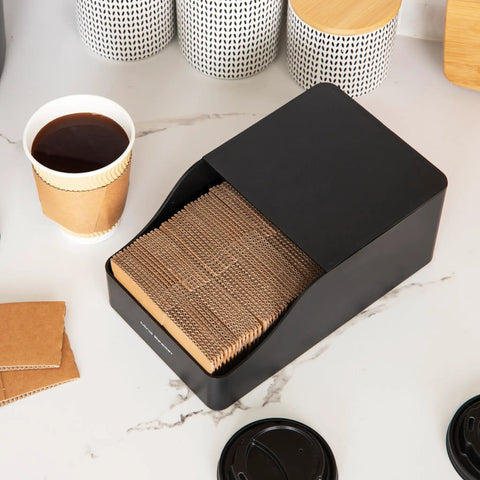 Hot Cup Sleeve Dispenser For Coffee Bar And Kitchen Organization, compact black unit with sleeves on a countertop
